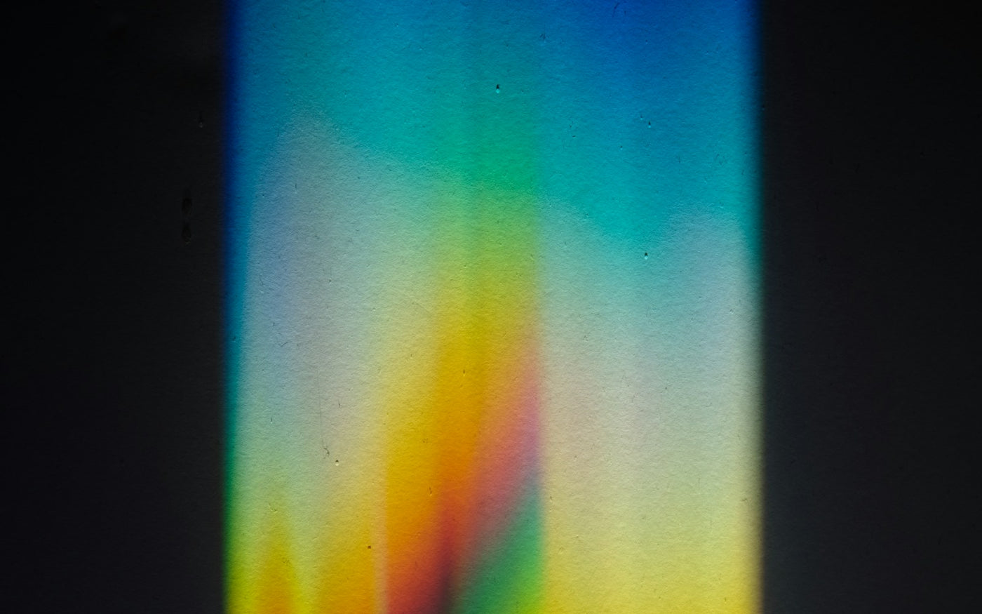 rainbow spectrum of refracted light on a dark wall