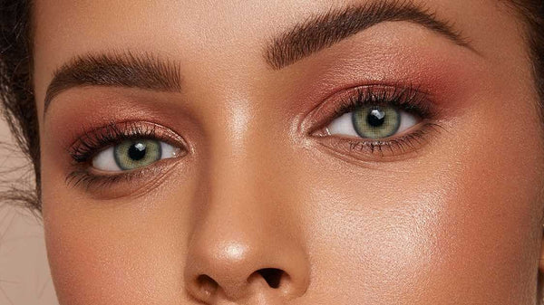 Gray-green colored contacts on a deep skin tone, editorial beauty close-up