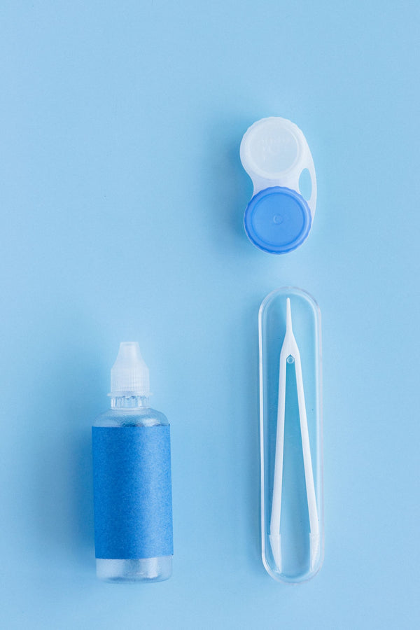 Contact lens case, solution bottle and tweezers flat lay