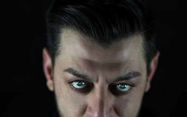 Man with striking pale colored contacts against a dark background