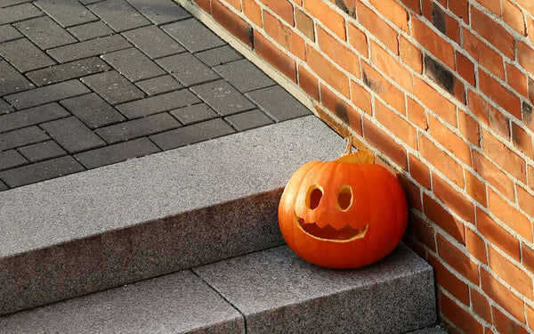 carved jack-o-lantern on front steps beside a brick wall