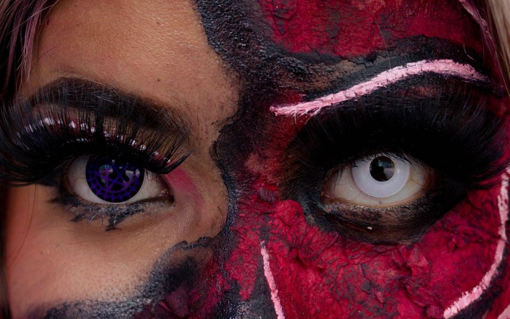 Halloween face paint look with purple and white colored contacts, one in each eye