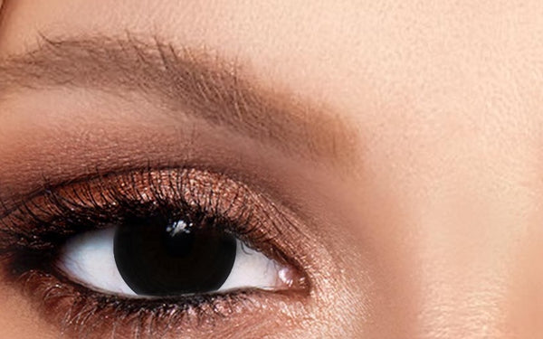 close-up of an eye wearing a blackout colored contact lens with bronze eyeshadow