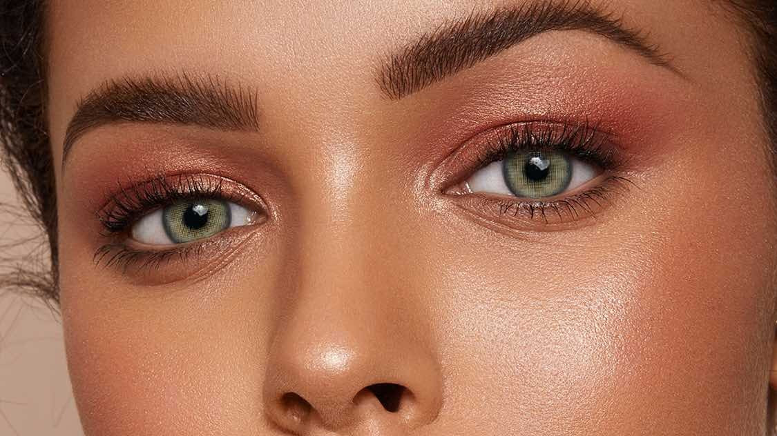 Gray-green colored contacts on a deep skin tone, editorial beauty close-up
