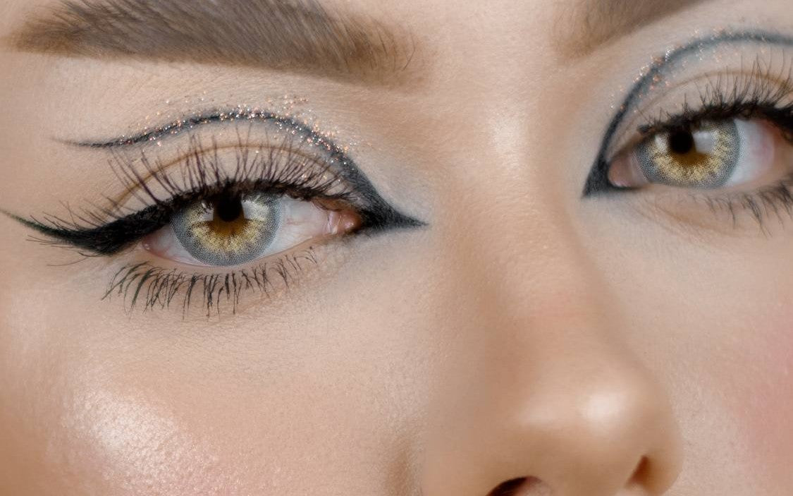 close-up of eyes wearing gray colored contact lenses with graphic eyeliner