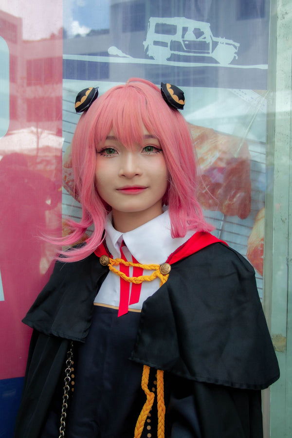 Cosplayer with pink hair and cape in full anime-style makeup