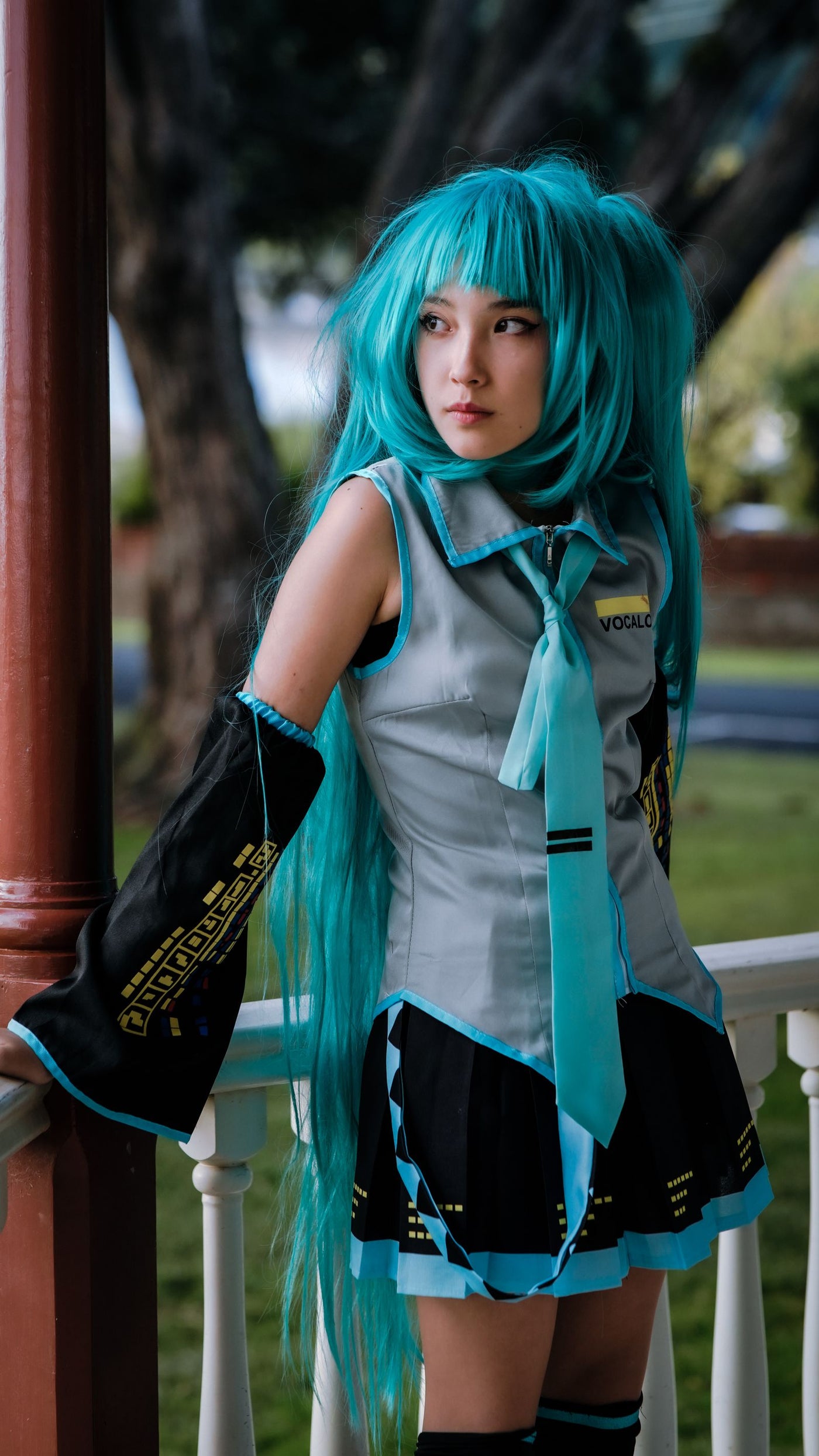 Cosplayer with teal wig photographed in soft outdoor light