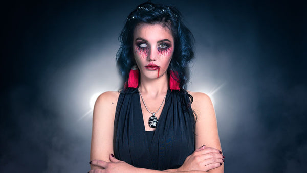Creepy Halloween makeup with one blanked-out white eye and a trickle of stage blood