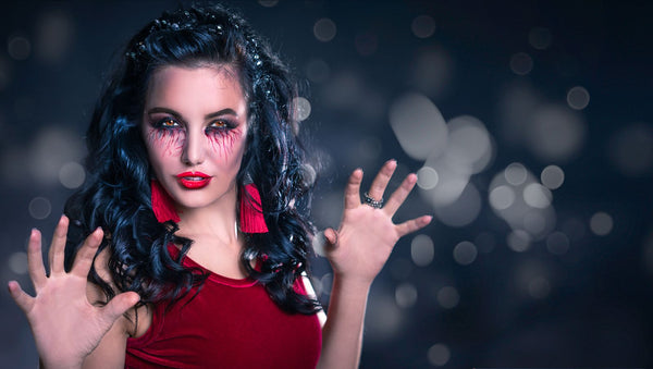 Dark-haired woman in blood-red dress with claw-posed hands — mid-transformation energy