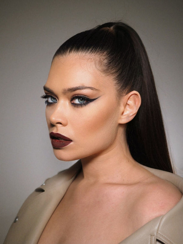 Studio portrait with sharp winged eyeliner and sleek ponytail — the classic cat-eye finish