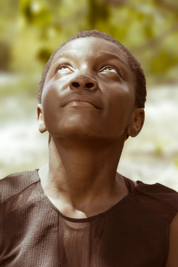 Portrait of a woman with deep skin tone gazing upward in warm sunlight