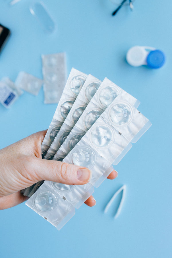 Hand holding sealed blister packs of contact lenses