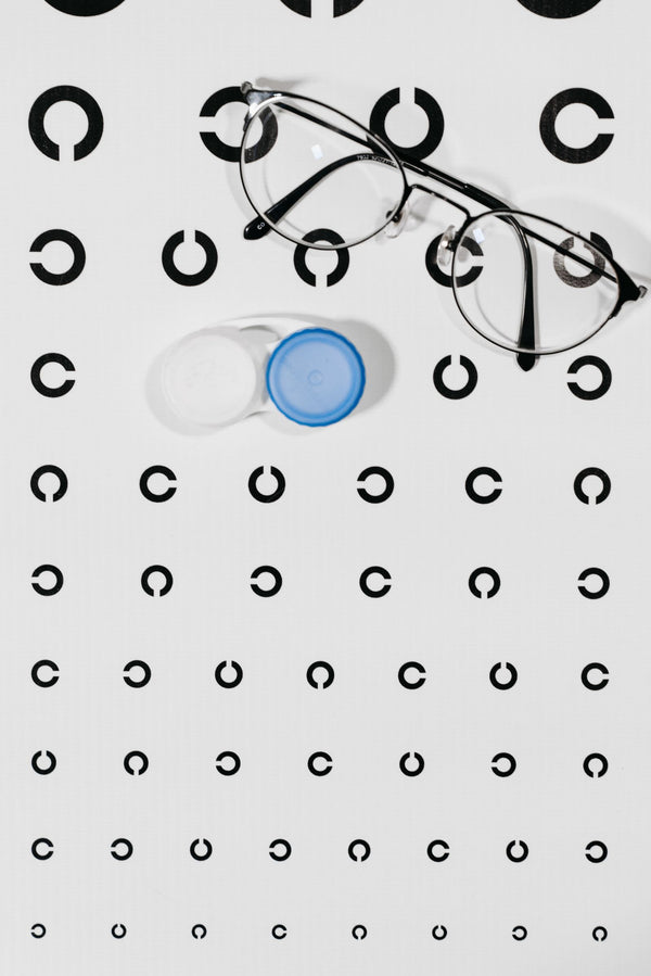 Eyeglasses and a contact lens case resting on an eye test chart