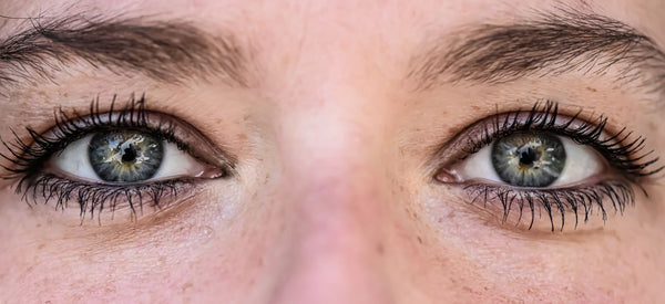 Extreme close-up of human eyes showing iris texture and light reflections