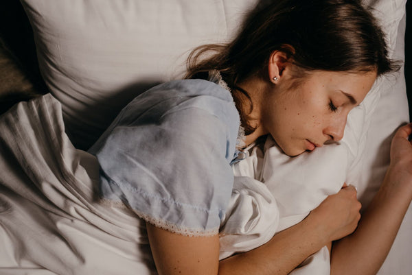 Woman asleep on a white pillow at night