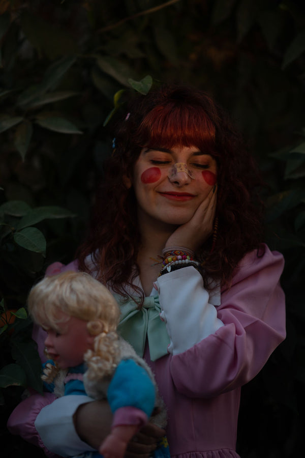 Woman in a pink ensemble holding a vintage doll